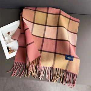 Detail of pink and yellow plaid cashmere-feel scarf with elegant tassels and woven label