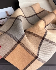 Close-up of soft plaid cashmere scarf texture with classic beige and brown fringe details