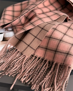 Close-up of soft plaid scarf showing orange-pink check pattern and tassel details