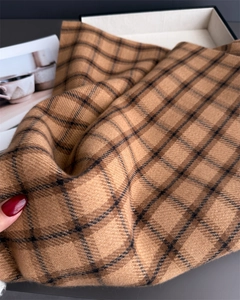 Detailed view of camel plaid scarf showing thick cashmere-like texture and soft fringes