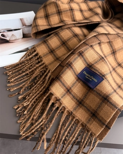 Close-up of camel plaid scarf with elegant classic label and tassel fringe detail