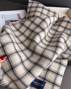 Close-up of classic plaid scarf texture with tassels and Elegant & Classic woven label