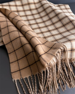 Detailed close-up of camel plaid cashmere-like scarf texture with delicate tassels