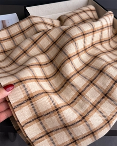 Detail of soft beige plaid cashmere scarf with woven texture in a premium gift box