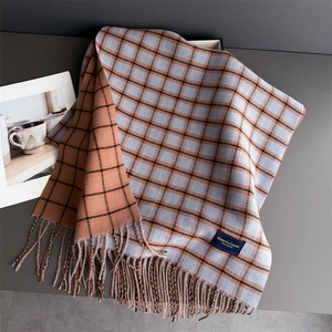 Detail of plaid scarf with fringe and Elegant & Classic label in orange and grey