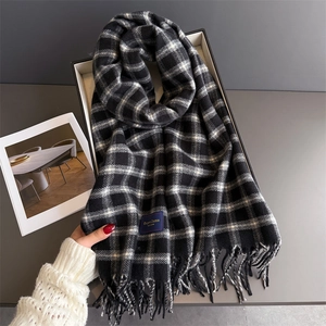 Close-up of the elegant classic label and tassel detail on the plaid cashmere-like scarf