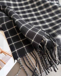 Detailed close-up of soft black and white plaid scarf featuring long decorative tassels