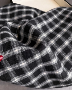 Macro detail of plaid scarf fabric featuring black and white twill weave with soft texture