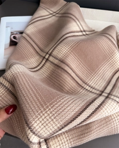 Close-up of soft cashmere-feel plaid scarf in beige and brown with hand-held texture detail