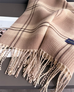 Close-up of beige and coffee plaid scarf with elegant fringe detail and woven label