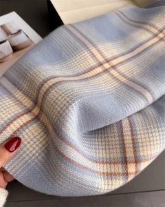 Close-up of soft plaid texture on blue and beige faux cashmere scarf with fringe