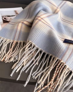 Close-up of soft plaid scarf fringe and woven label in blue and beige checkered pattern