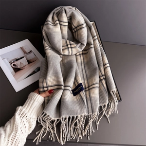 Close-up of gray plaid scarf with Elegant & Classic woven label and soft fringe trim