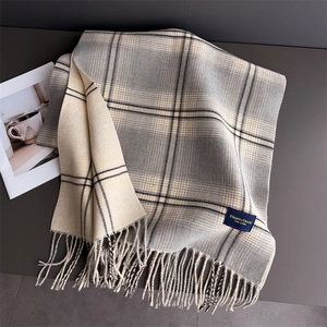 Macro view of plaid cashmere-like scarf with grey beige check patterns and soft fringe detail