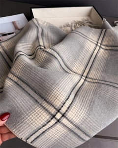 Close-up of soft grey and beige plaid scarf showing high-quality tassel fringe detail