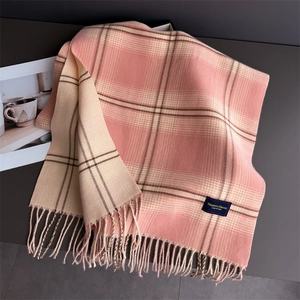 Macro detail of plaid cashmere-like scarf showing soft texture and fine fringe edge