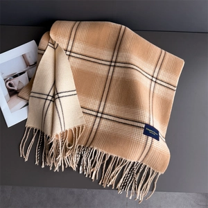 Detail of double-sided camel plaid scarf with elegant fringe and woven brand label