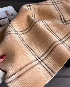 Macro detail of soft plaid cashmere texture with elegant hand-held fabric draping