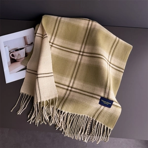 Detail of green plaid cashmere scarf featuring fine fringe and elegant woven texture