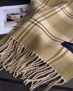 Close-up of green and beige plaid scarf with soft tassels and brand label detail