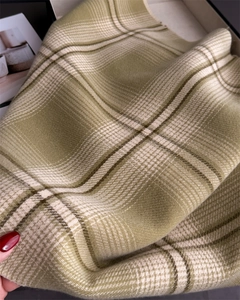 Close-up of soft green plaid cashmere scarf with brushed texture and classic fringe