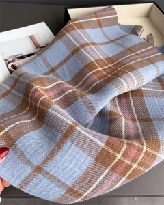 Gros plan d'une écharpe à carreaux bleu et marron doux avec des détails de franges