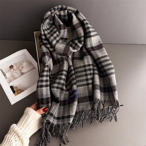 Detailed macro shot of grey British plaid scarf featuring hand-knotted fringe and classic label