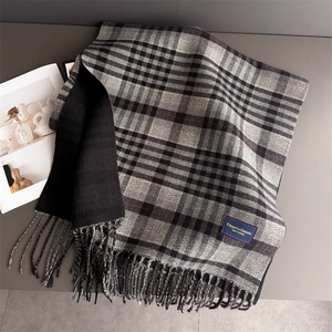 Close-up of classic grey and black plaid scarf with red stripes and fringe edge detail