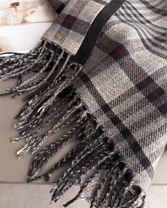 Close-up of gray plaid scarf showing soft cashmere texture and neat fringe details