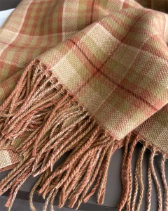 Detailed macro view of orange and beige plaid scarf texture with soft fringed edges