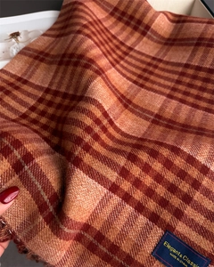 Close-up of soft plaid scarf fabric with elegant brand label and fringe detail