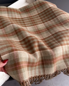 Detailed view of the plaid wool-like scarf texture featuring fringes and soft drape
