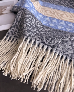 Close-up of geometric knit scarf with fringe trim in blue and grey ethnic patterns