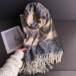 Detail of bohemian fringed scarf with geometric patterns in beige and grey soft cashmere feel