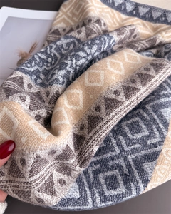 Close-up of geometric knit pattern on thick warm shawl with soft fringe texture