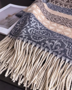 Detail of bohemian geometric knit scarf featuring soft cream fringe and woven texture