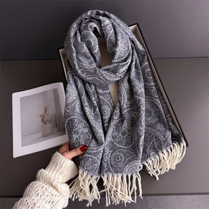 Detail of grey cashmere-feel scarf featuring intricate paisley patterns and long tassels