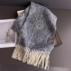 Close-up of grey paisley pattern cashmere-like scarf with white fringe in a gift box
