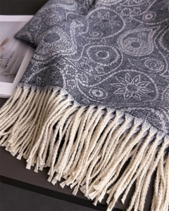 Close-up of grey paisley pattern cashmere shawl with soft decorative cream tassels