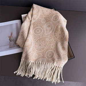 Detail of beige paisley pashmina scarf with soft fringes on a black gift box