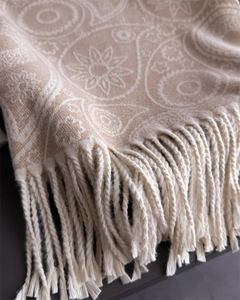Detailed macro view of beige paisley pashmina fabric with elegant white tassels