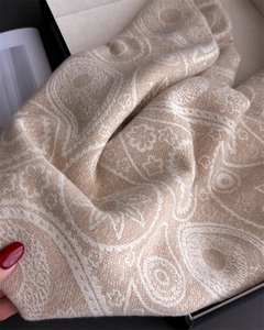 Detail of paisley pattern on beige cashmere-like scarf inside a black gift box