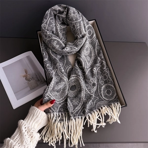 Close-up of off-white paisley cashmere scarf with cream fringes on a minimalist display