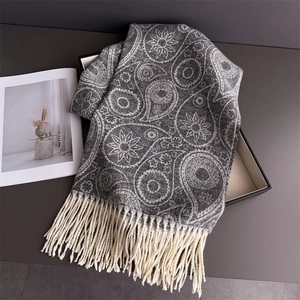 Close-up of grey paisley cashmere scarf with thick cream tassels on minimalist tray