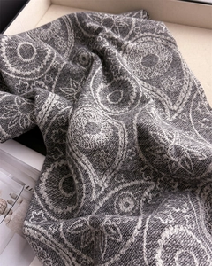 Close-up of gray paisley pattern cashmere-like scarf with intricate woven texture detail
