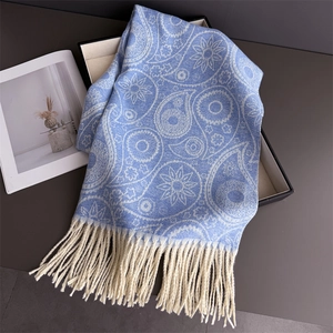 Detail of light blue paisley jacquard scarf showing thick tassels and soft texture