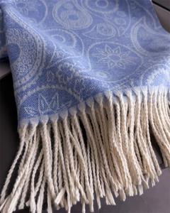 Macro view of light blue paisley cashmere scarf with fine off-white tassel details