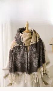 Detail of floral imitation cashmere scarf with tassels and geometric patterns in warm tones