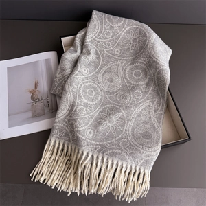 Detailed view of paisley jacquard pattern and soft fringe on cashmere-feel winter scarf