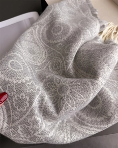 Close-up of grey paisley jacquard scarf fabric with elegant soft fringe tassels